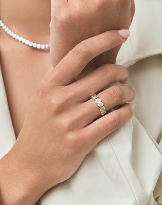 Close-up model wears Tournon 0.20ct oval bezel set half eternity band in 18ct yellow gold