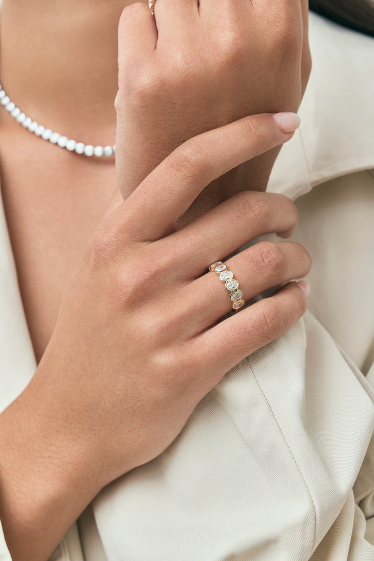 Close-up model wears Tournon 0.20ct oval bezel set half eternity band in 18ct yellow gold