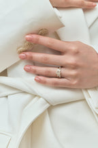 Close-up model wears Bruton emerald cut pear side stone engagement ring in 18ct yellow gold