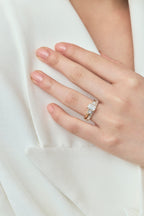 Close-up model wears Bruton emerald cut pear side stone engagement ring in 18ct yellow gold