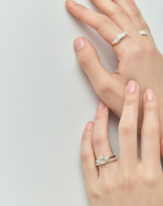 Close-up model wears Bruton emerald cut pear side stone engagement ring in 18ct yellow gold