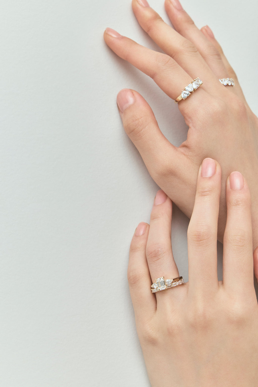 Close-up model wears Bruton emerald cut pear side stone engagement ring in 18ct yellow gold