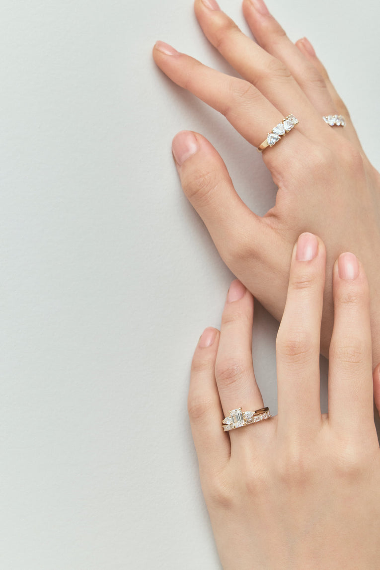 Close-up model wears Bruton emerald cut pear side stone engagement ring in 18ct yellow gold