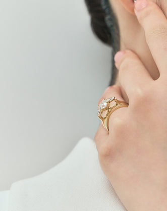Model wears Cornelia round brilliant pear side stone engagement ring with lab-grown diamond band in 18ct yellow gold
