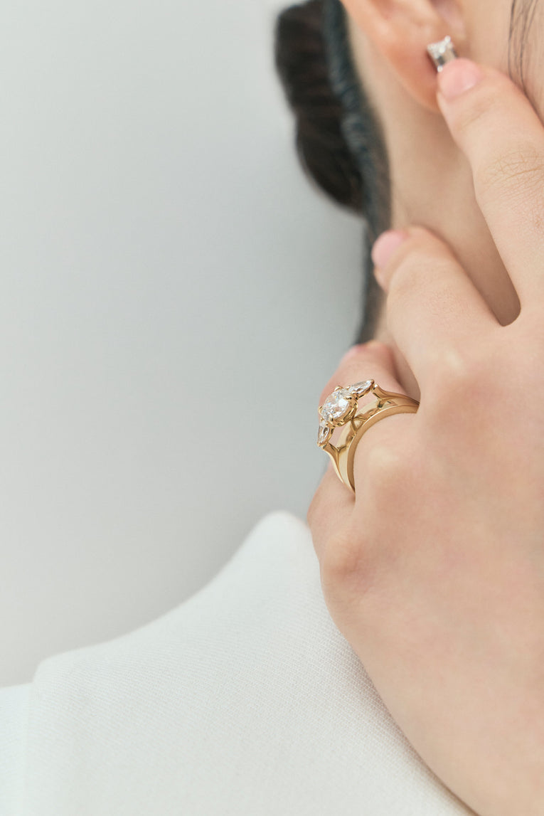 Model wears Cornelia round brilliant pear side stone engagement ring with lab-grown diamond band in 18ct yellow gold