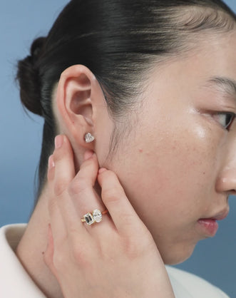 Close-up model wears Bowery Toi Et Moi oval emerald engagement ring in 18ct yellow gold