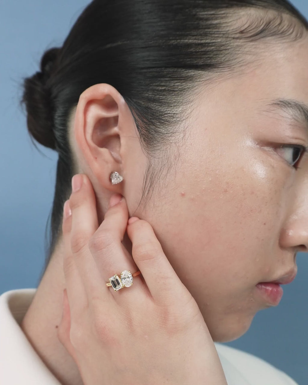 Close-up model wears Bowery Toi Et Moi oval emerald engagement ring in 18ct yellow gold
