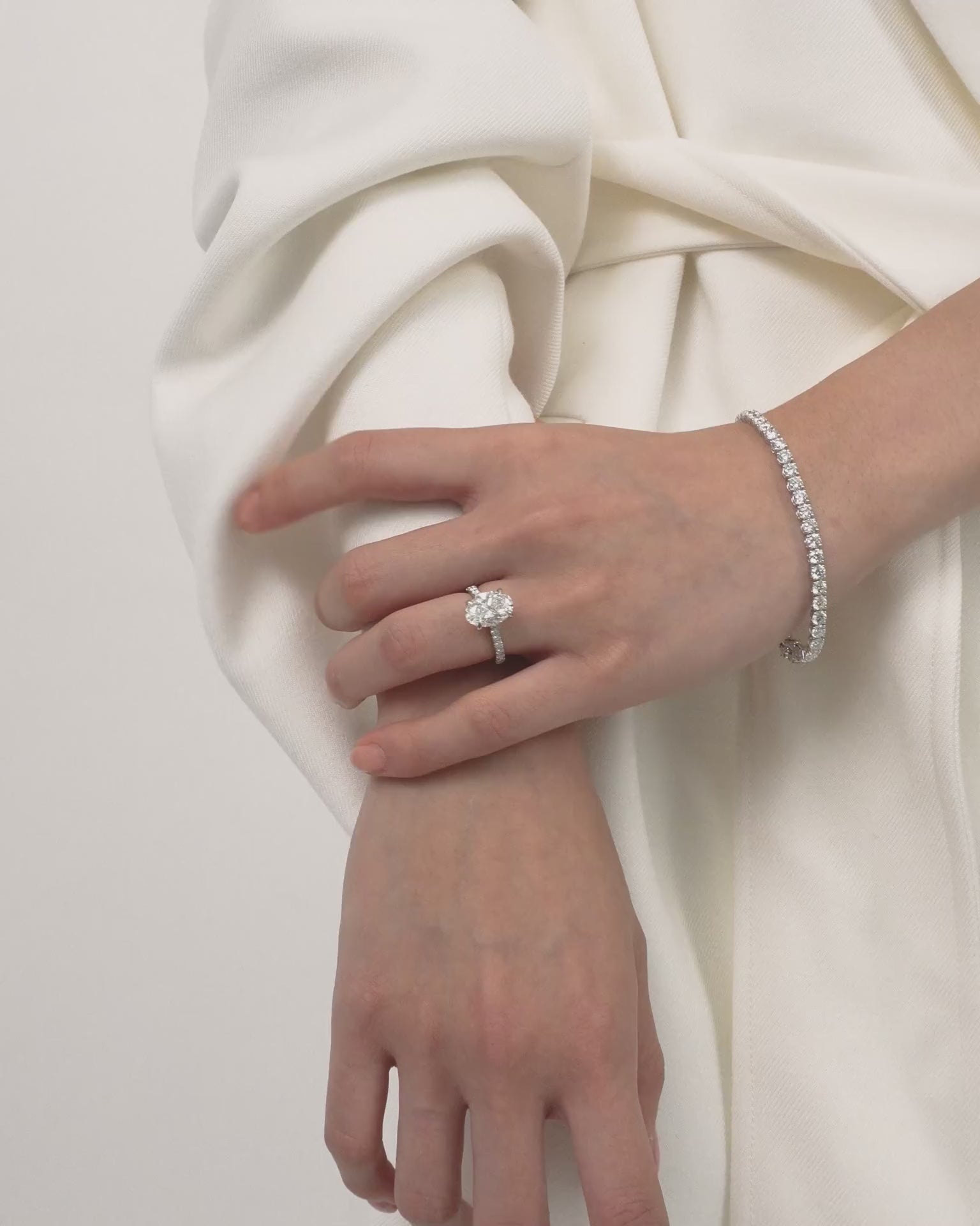 Model wears Nassau oval cut diamond band engagement ring in 18ct white gold