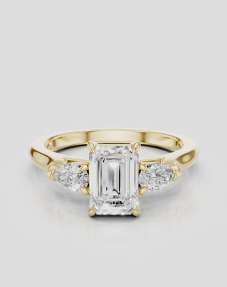 Bruton emerald cut pear side stone engagement ring in 18ct yellow gold