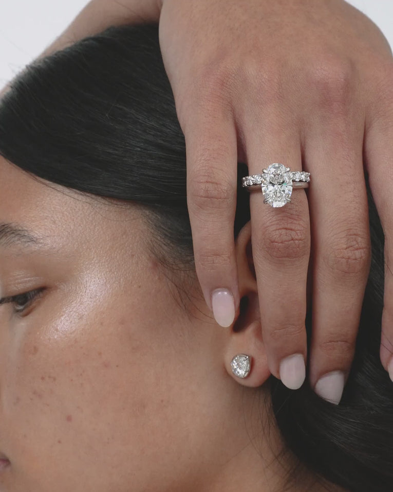 Model wears Montaigne oval solitaire swept shoulder engagement ring in platinum