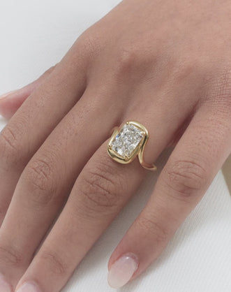 Model wears Prince 3ct radiant cut curved band engagement ring in 18ct yellow gold